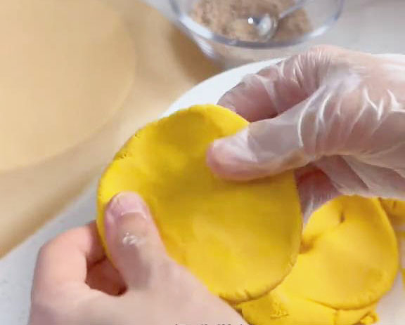 Take a 50g portion of the dough and flatten it into a disc