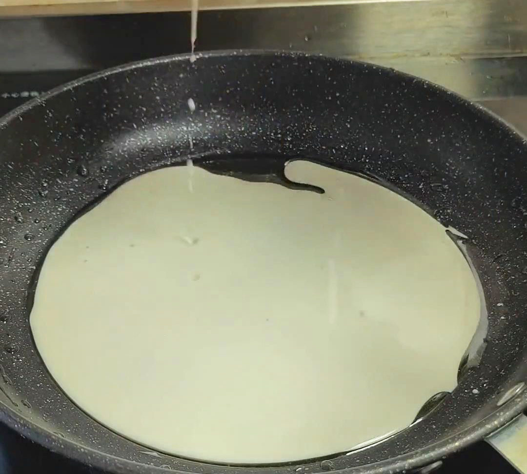 Pour a ladleful of the batter into the hot pan