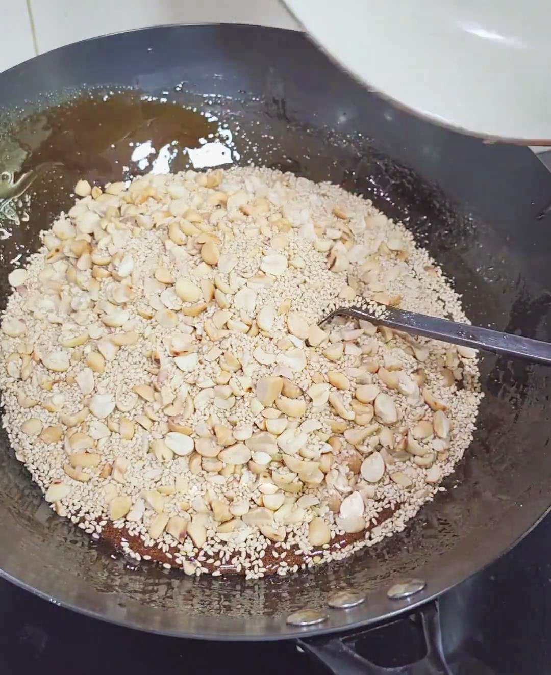 add the prepared peanuts and toasted sesame seeds to the syrup