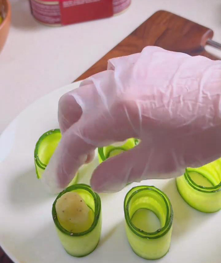 Carefully place each ball inside a cucumber roll and press them down to flatten