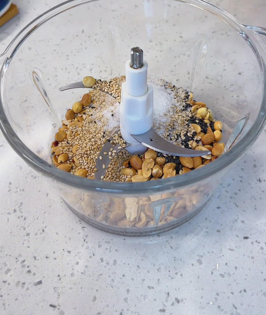 Add the roasted peanuts, black sesame seeds, white sesame seeds, and sugar into a food processor Add the roasted peanuts, black sesame seeds, white sesame seeds, and sugar into a food processor