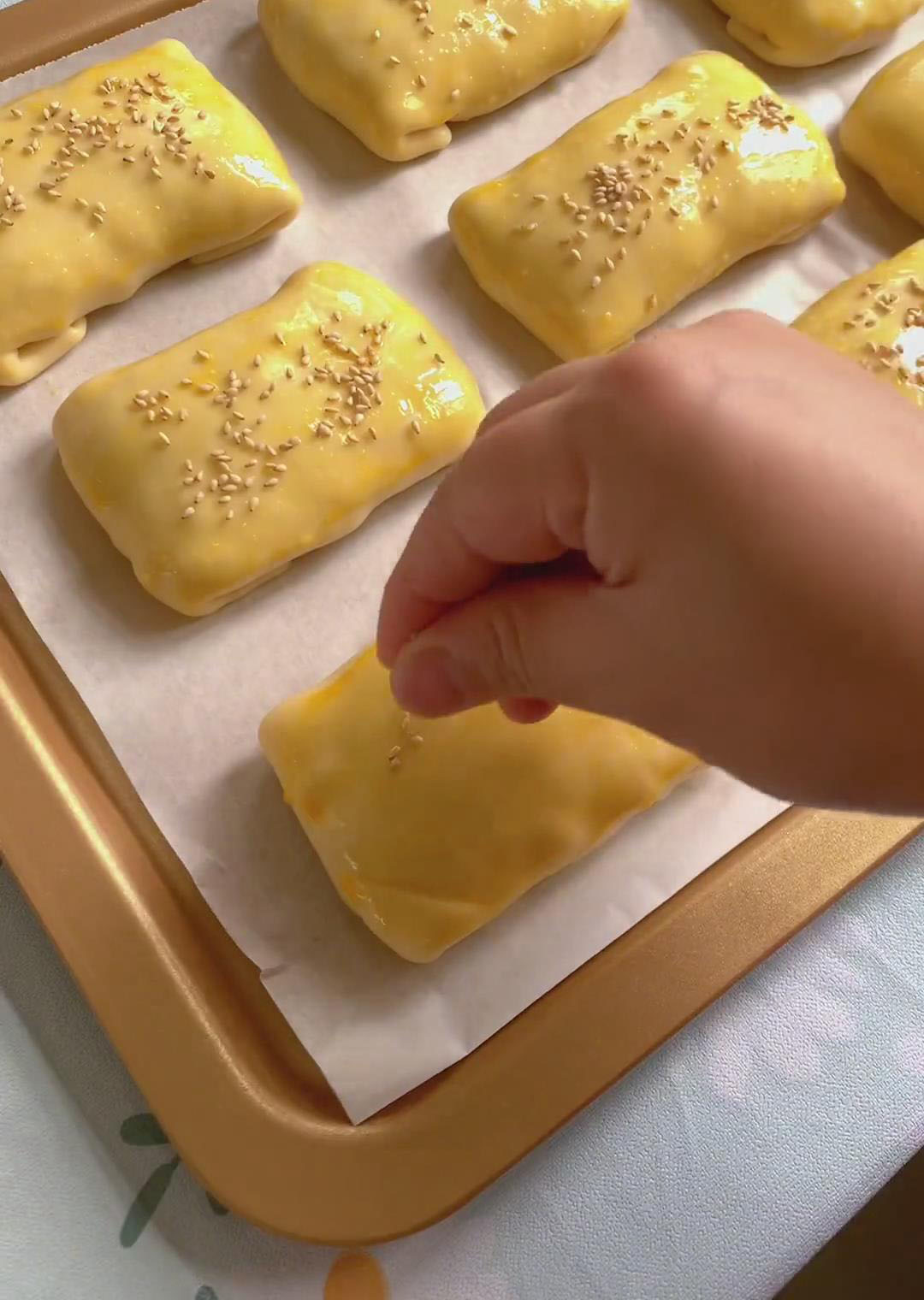 Brush the surface of each bun evenly with beaten egg and sprinkle with white sesame seeds