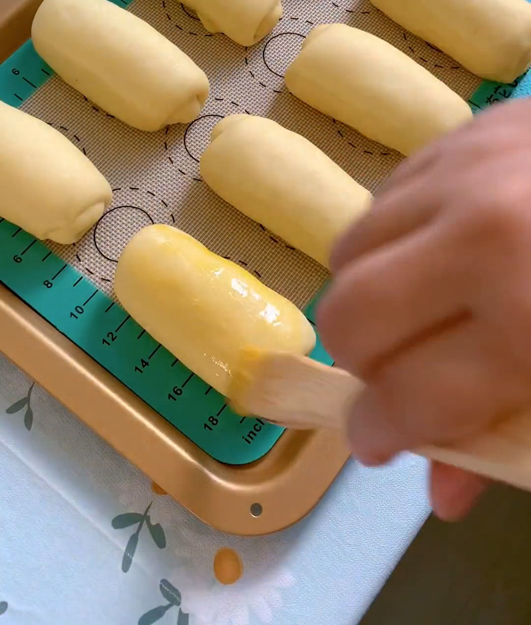 Remove the tray and brush the surface of the buns evenly with egg wash
