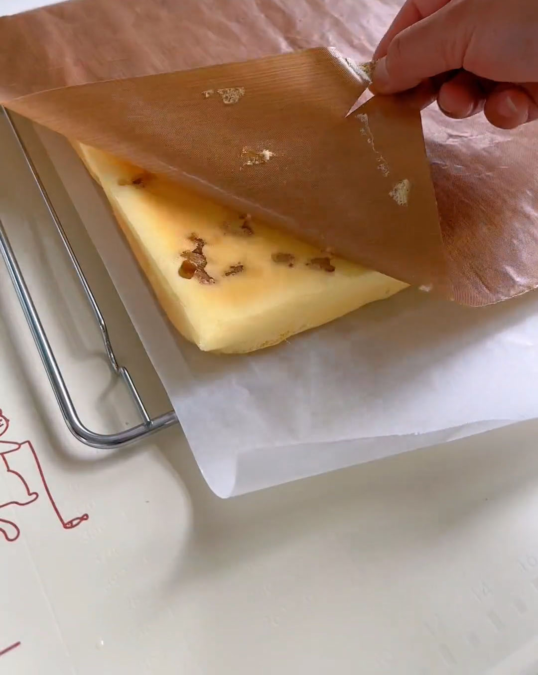 invert the warm cake onto this new paper and peel off the baked parchment layer from the bottom (now the top)