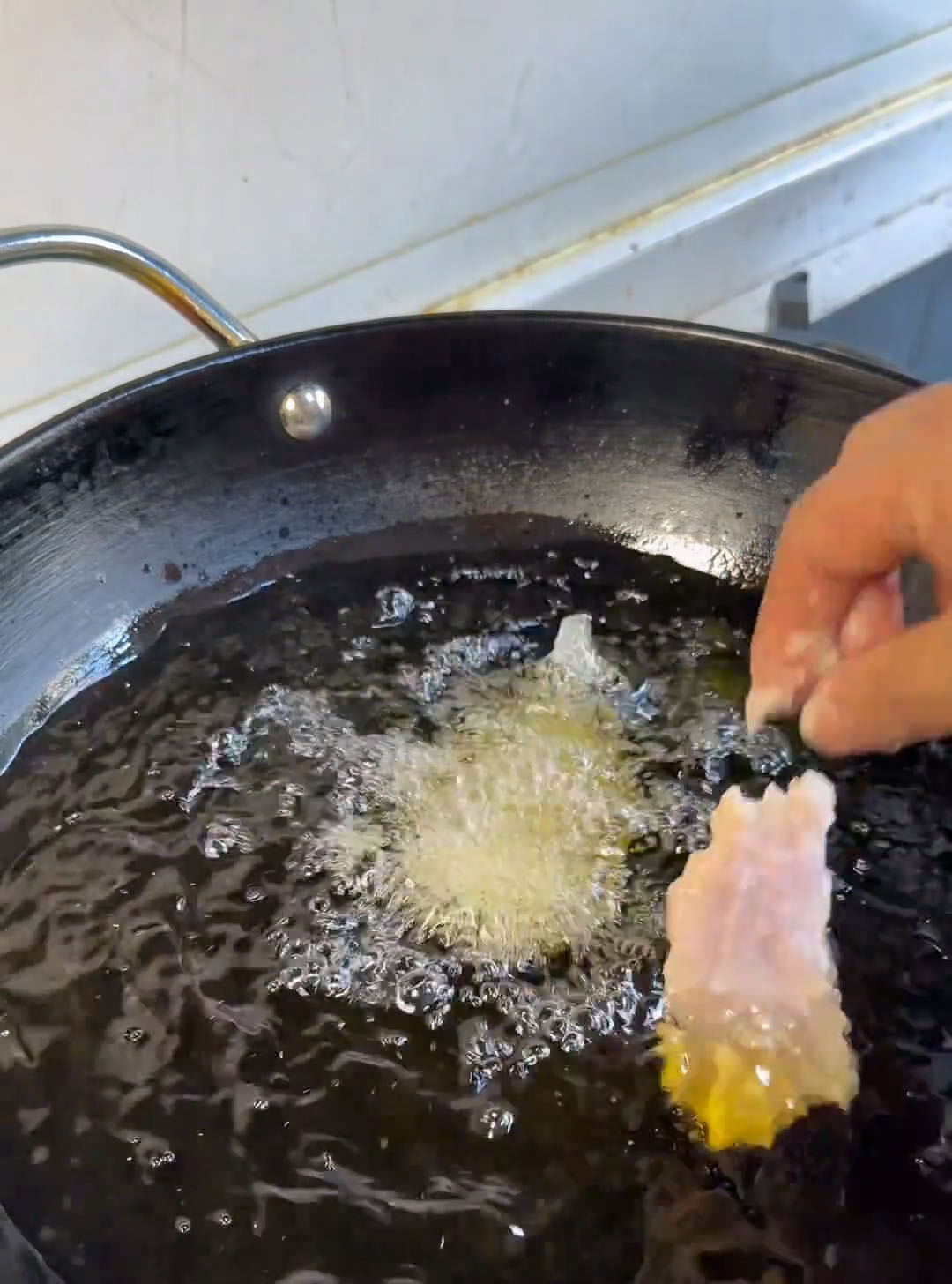Carefully add the battered pork slices one by one